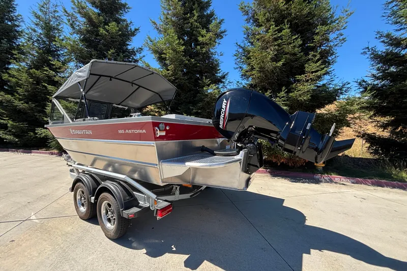 Slide: The Image of 2025 Spartan 185 Astoria boat on trailer, featuring Mercury outboard motor, parked outdoors. - 5