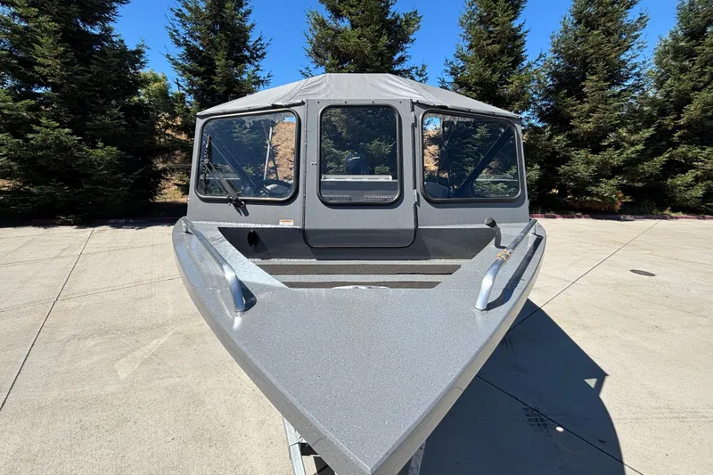 Slide: The Image of 2025 Spartan 185 Astoria boat, front view, parked on concrete with trees in background. - 12