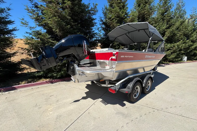 Slide: The Image of 2025 Spartan 185 Astoria boat on trailer, parked outdoors with trees in background. - 4