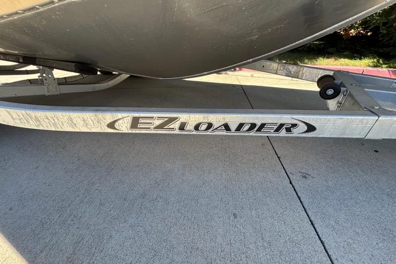 Slide: The Image of EZ Loader trailer supporting a 2025 Spartan 185 Astoria boat on concrete pavement. - 36