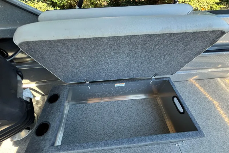 Slide: The Image of Open storage compartment in 2025 Spartan 185 Astoria boat, featuring cup holders and cushioned seat. - 43