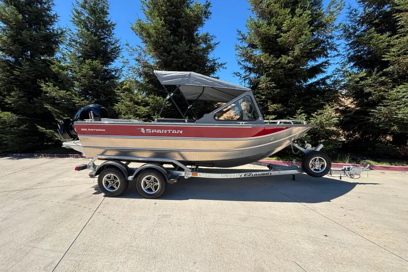 The Image of 2025 Spartan 185 Astoria boat on trailer, parked outdoors with trees in background. - 0