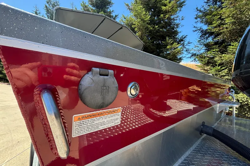 Slide: The Image of Red Spartan 185 Astoria boat, 2025 model, with fuel cap and warning label, surrounded by trees. - 11