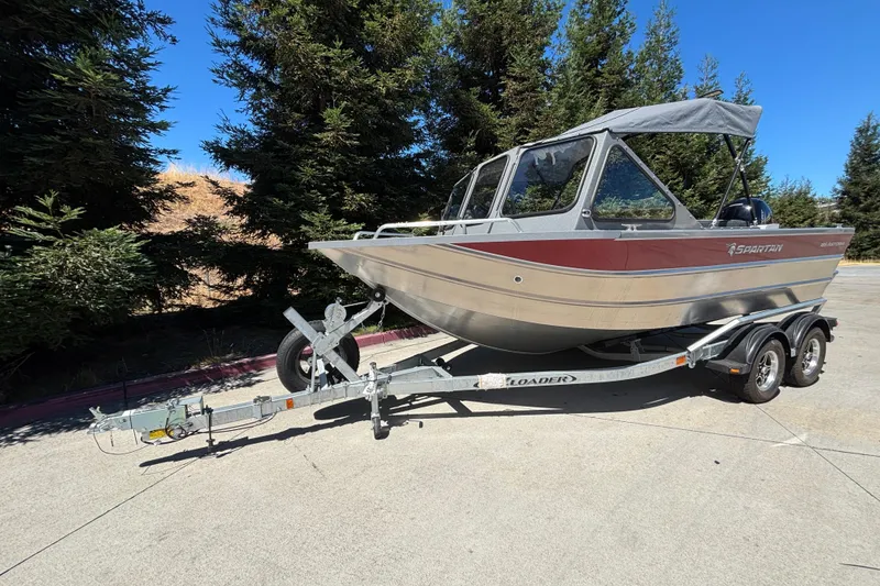 Slide: The Image of 2025 Spartan 185 Astoria boat on trailer, parked outdoors near trees. - 3
