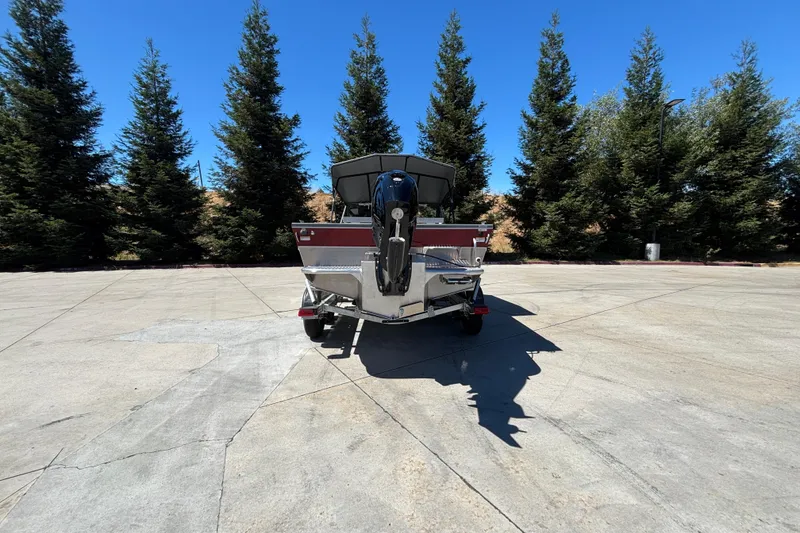 Slide: The Image of 2025 Spartan 185 Astoria boat on trailer, surrounded by tall trees under clear blue sky. - 14