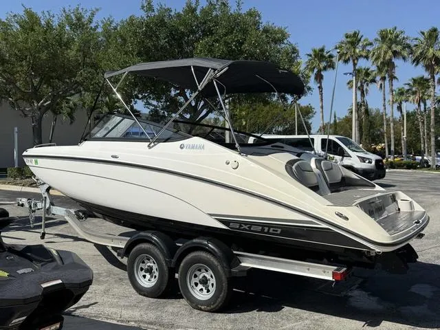 Slide: The Image of 2018 Yamaha Boats SX210 on trailer, parked outdoors with trees in the background. - 17