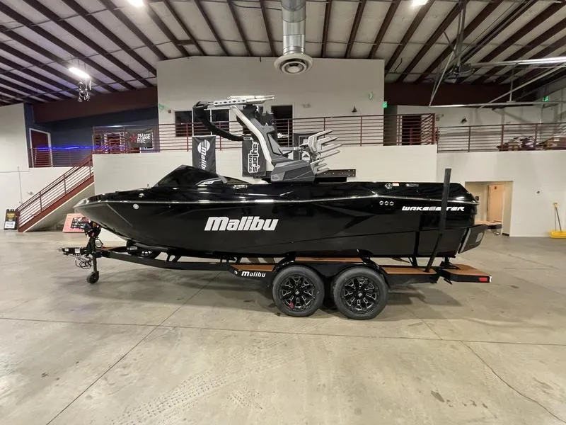 Slide: The Image of 2025 Malibu 23 LSV boat in showroom, black exterior, on trailer. - 1
