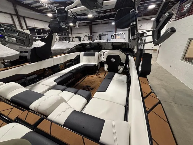 Slide: The Image of 2025 Malibu 23 LSV boat interior with luxurious seating in a showroom. - 14