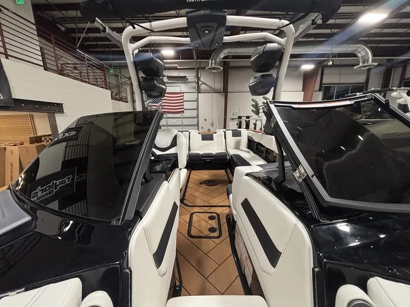 Slide: The Image of 2025 Malibu 23 LSV boat interior with sleek black and white seating in a showroom. - 21