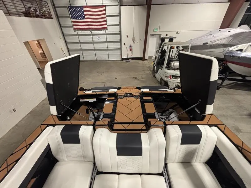 Slide: The Image of 2025 Malibu 23 LSV boat interior with white seating in a garage setting. - 23
