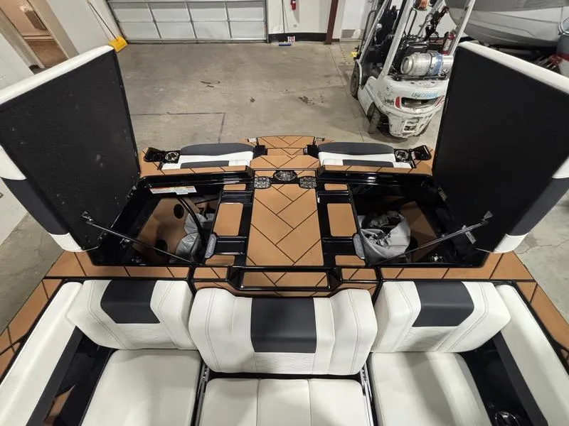 Slide: The Image of 2025 Malibu 23 LSV boat interior with open storage compartments and white seating. - 25