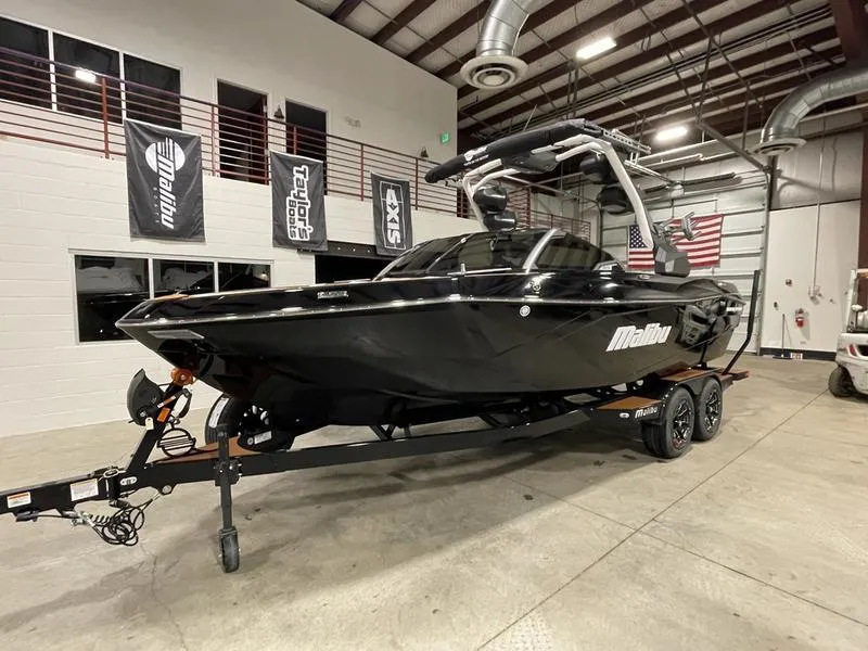 Slide: The Image of 2025 Malibu 23 LSV boat in showroom, black exterior, on trailer. - 4