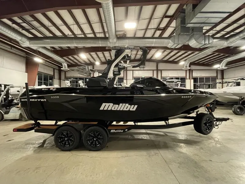 Slide: The Image of 2025 Malibu 23 LSV boat in showroom, black exterior, on trailer. - 6