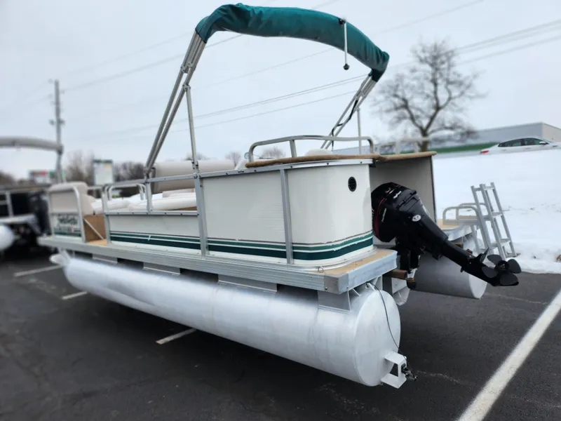 Slide: The Image of Sweetwater 180 pontoon boat, 2000 model, parked on snowy pavement with green canopy. - 3