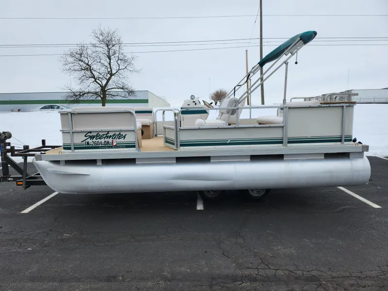 Slide: The Image of 2000 Sweetwater 180 pontoon boat parked on asphalt, featuring green accents and a canopy. - 4