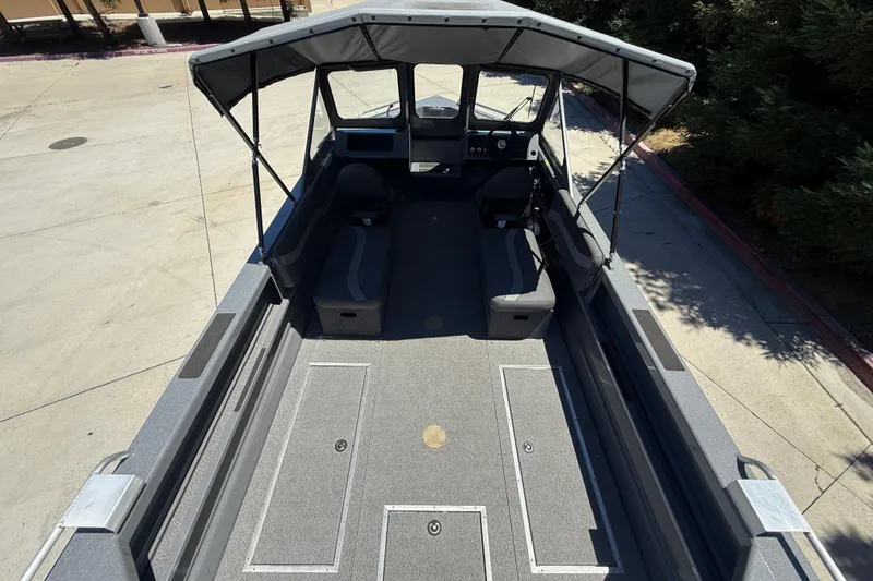 Slide: The Image of 2025 Spartan 200 Astoria boat interior with seating and canopy, parked outdoors. - 27