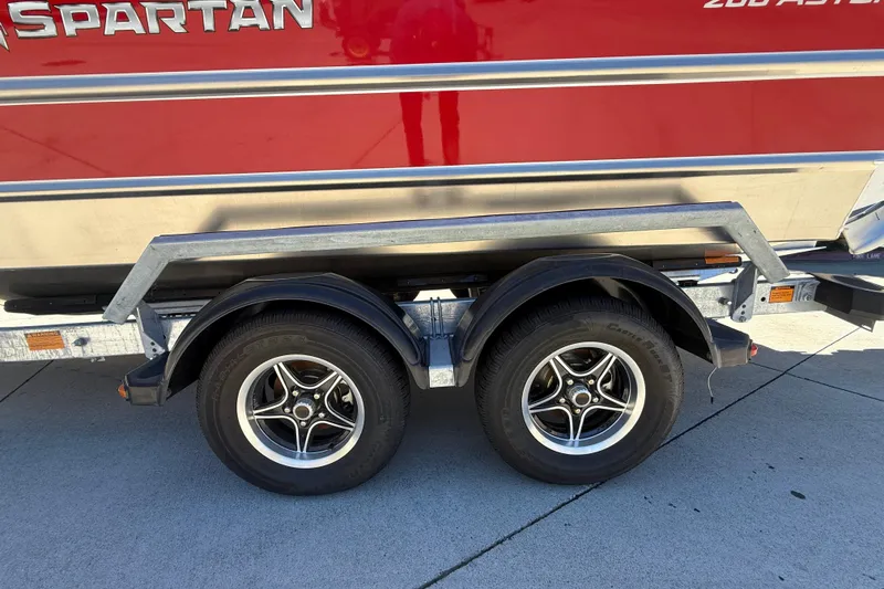 Slide: The Image of Trailer with dual wheels for 2025 Spartan 200 Astoria boat, red exterior. - 16