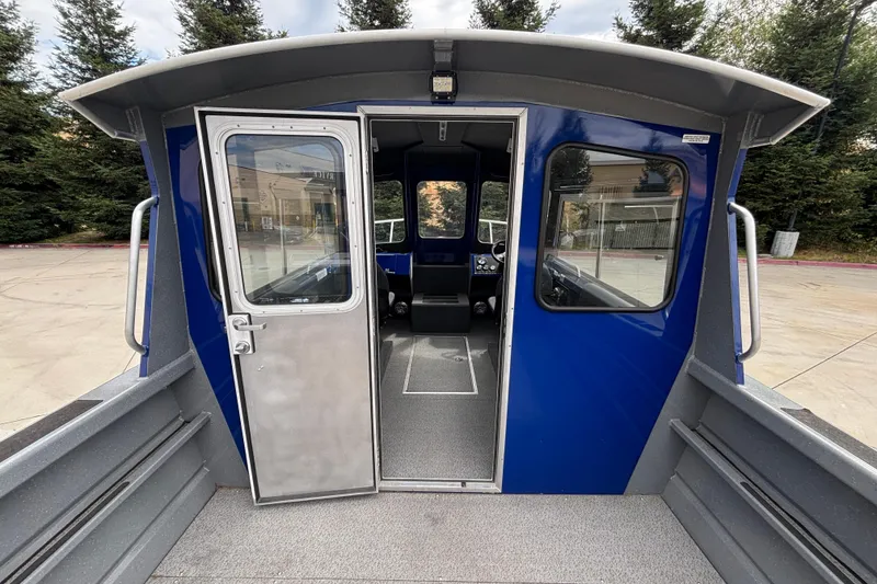 Slide: The Image of 2025 Spartan 240 Maximus Pro boat interior with open door, blue exterior, and visible cockpit. - 20