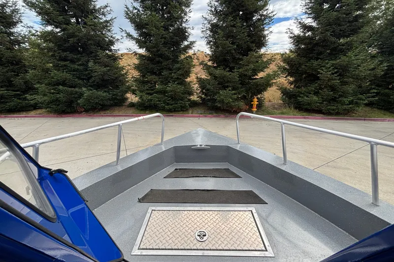 Slide: The Image of Bow view of 2025 Spartan 240 Maximus Pro boat, parked near trees and pavement. - 12