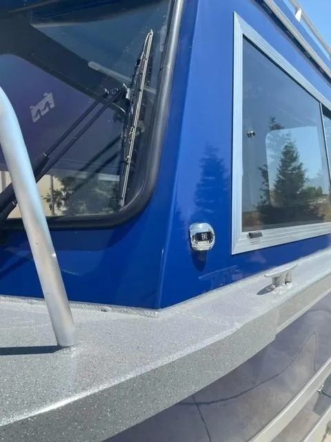 Slide: The Image of 2025 Spartan 240 Maximus Pro boat, blue exterior, close-up of window and railing. - 3