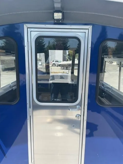 Slide: The Image of 2025 Spartan 240 Maximus Pro, blue exterior, featuring a sleek metal door with windows. - 7