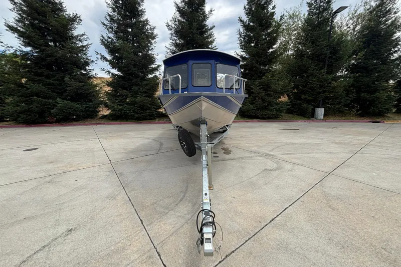 Slide: The Image of Front view of 2025 Spartan 240 Maximus Pro boat on trailer, surrounded by trees. - 3