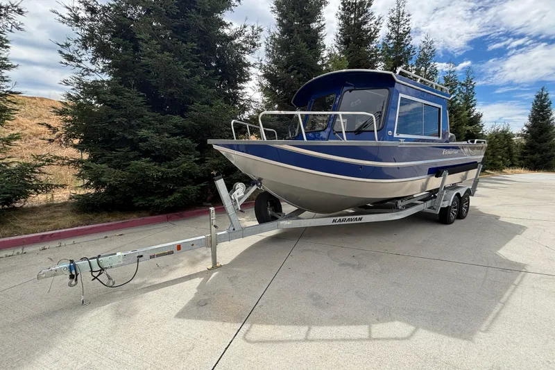 Slide: The Image of 2025 Spartan 240 Maximus Pro boat on trailer, parked outdoors with trees in background. - 2