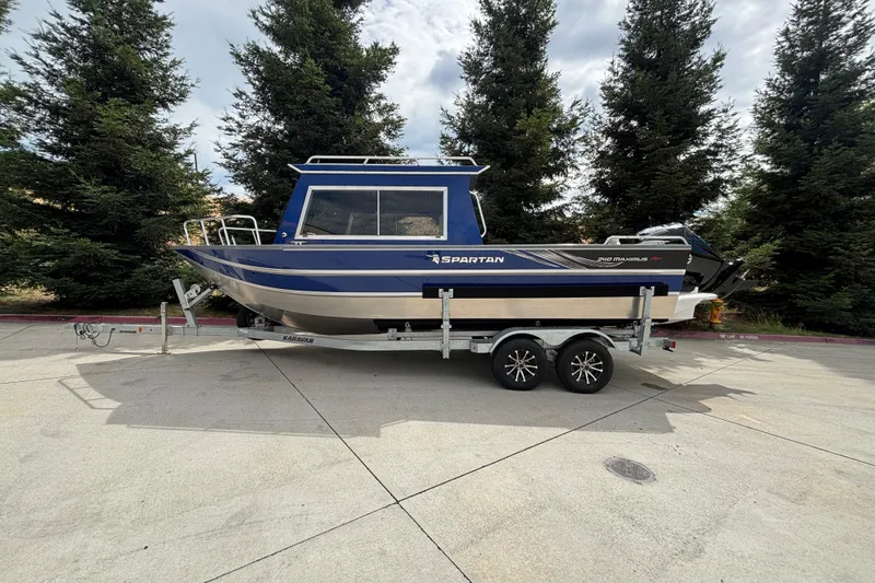 The Image of 2025 Spartan 240 Maximus Pro boat on trailer, parked outdoors with trees in background. - 0