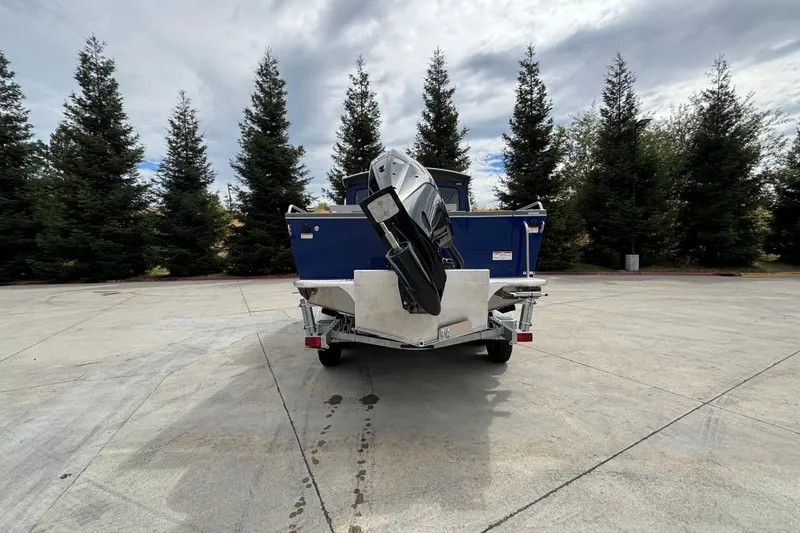 Slide: The Image of Rear view of 2025 Spartan 240 Maximus Pro boat on trailer, surrounded by trees. - 7