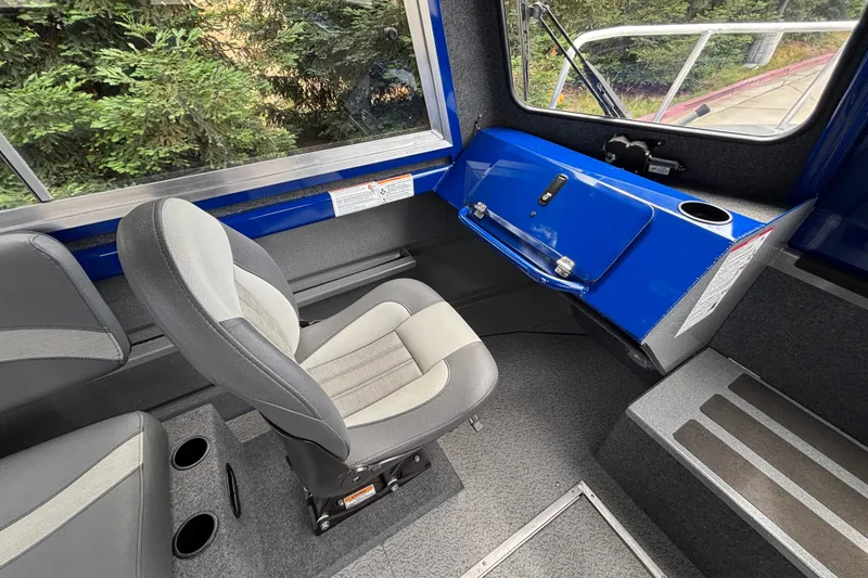 Slide: The Image of Interior of 2025 Spartan 240 Maximus Pro boat with gray seating and blue dashboard. - 16
