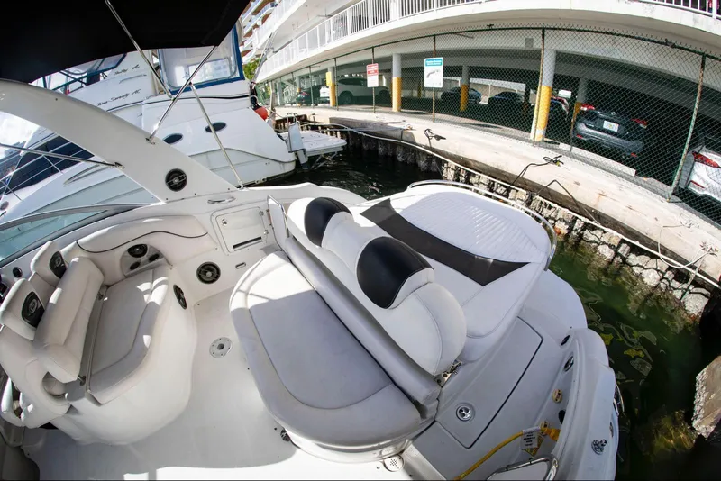 Slide: The Image of 2006 Crownline 320 LS boat interior with white seating, docked near a marina. - 15