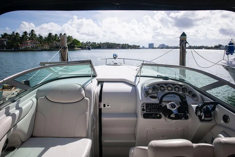 Slide: The Image of 2006 Crownline 320 LS boat interior with steering wheel, docked by a scenic waterfront. - 16