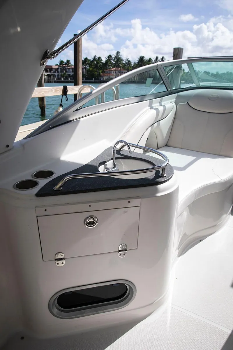 Slide: The Image of 2006 Crownline 320 LS boat interior with seating and sink, docked by the water. - 18