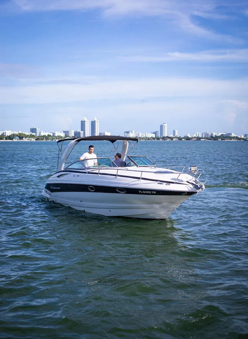 Slide: The Image of 2006 Crownline 320 LS boat cruising on a sunny day with city skyline in background. - 3
