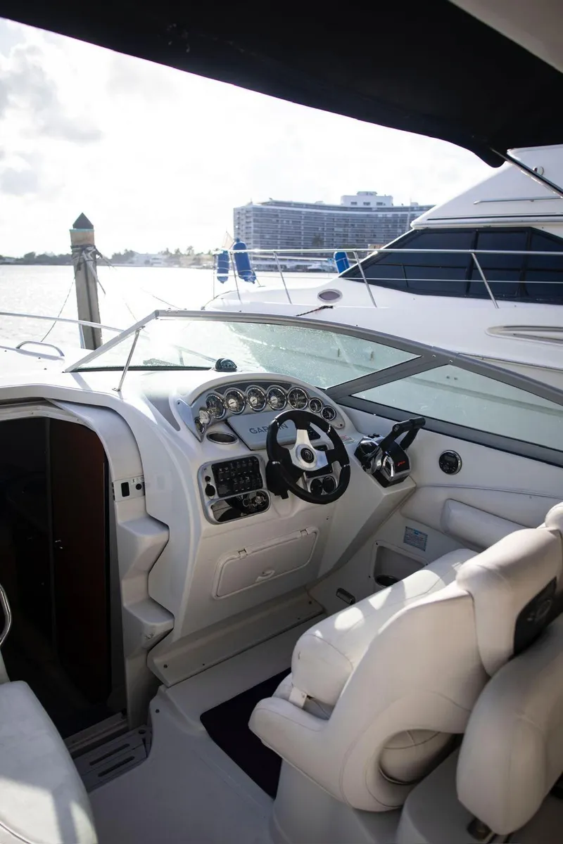 Slide: The Image of 2006 Crownline 320 LS boat cockpit with steering wheel and controls, docked by the water. - 7