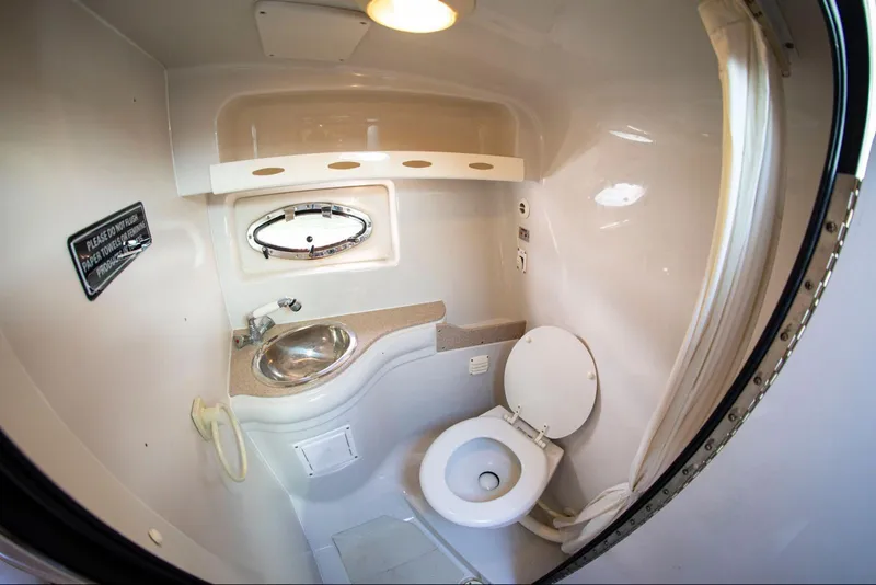 Slide: The Image of 2006 Crownline 320 LS boat bathroom with sink, toilet, and porthole window. - 9
