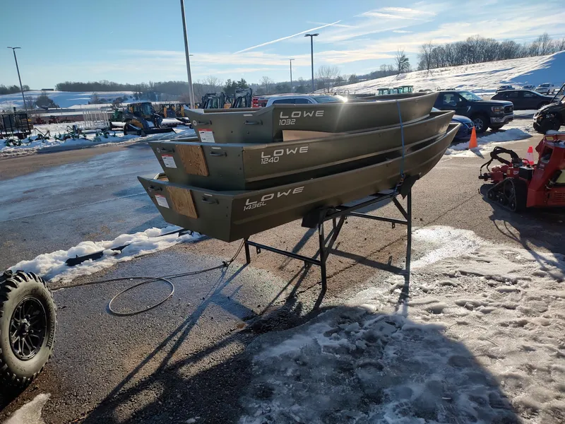 Slide: The Image of 2025 Lowe Jon L1436L boats stacked outdoors on a snowy day. - 5