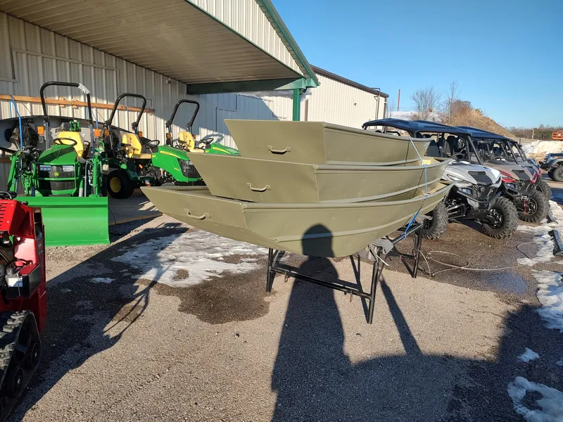 Slide: The Image of 2025 Lowe Jon L1436L boats stacked outdoors near tractors and ATVs. - 9