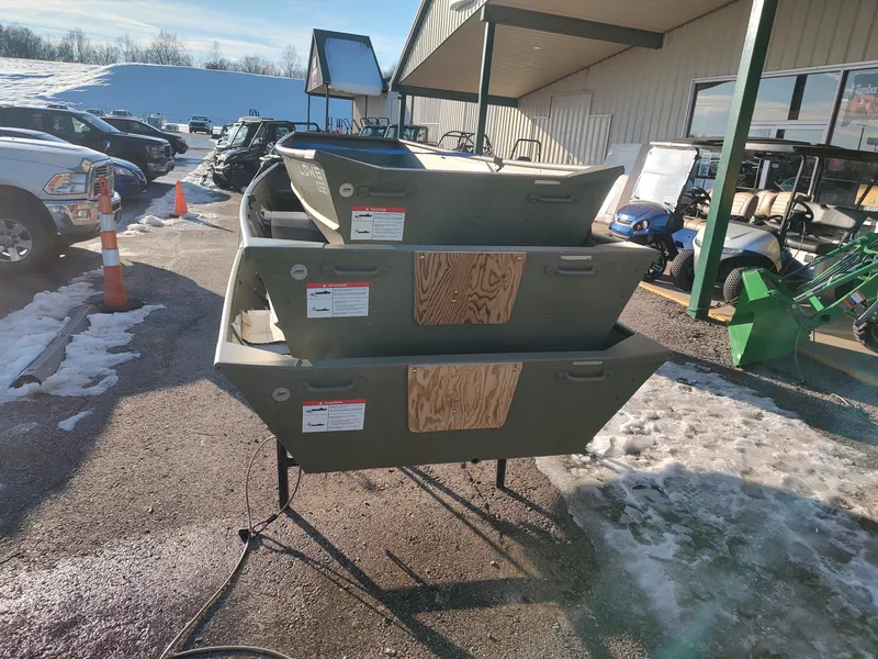 Slide: The Image of 2025 Lowe Jon L1240 boats stacked outdoors on a snowy day at a dealership. - 7
