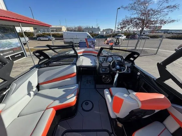 Slide: The Image of 2019 Axis A24 boat interior with modern dashboard and seating, parked outdoors. - 12