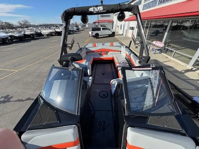 Slide: The Image of 2019 Axis A24 boat with open deck and seating, parked near a dealership. - 14