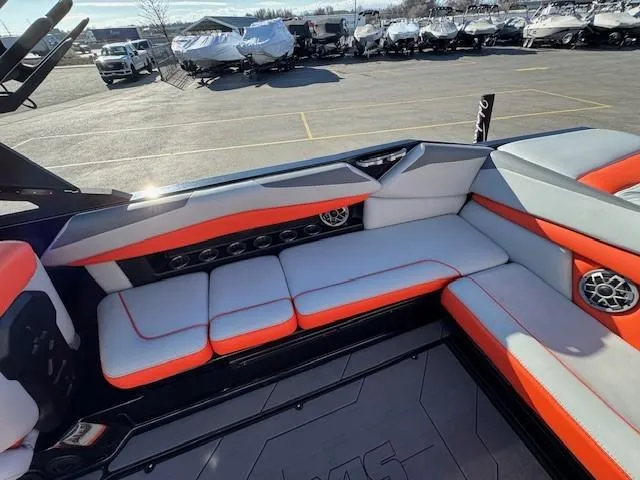 Slide: The Image of 2019 Axis A24 boat interior with orange and gray seating, parked in a lot. - 18