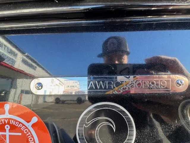 Slide: The Image of Reflection on Axis A24 2019 boat with safety inspection sticker and wave logo. - 22