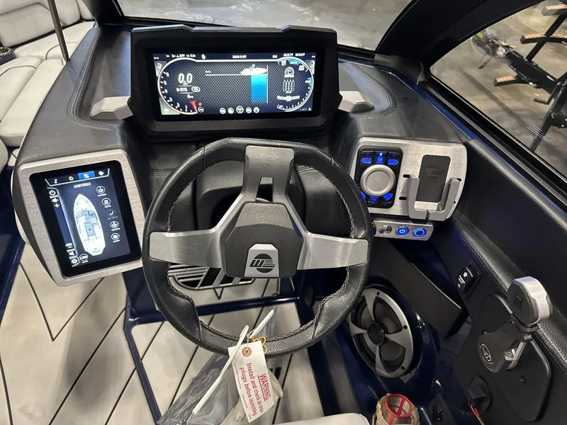 Slide: The Image of 2021 Malibu 25 LSV boat dashboard with digital displays and steering wheel. - 10