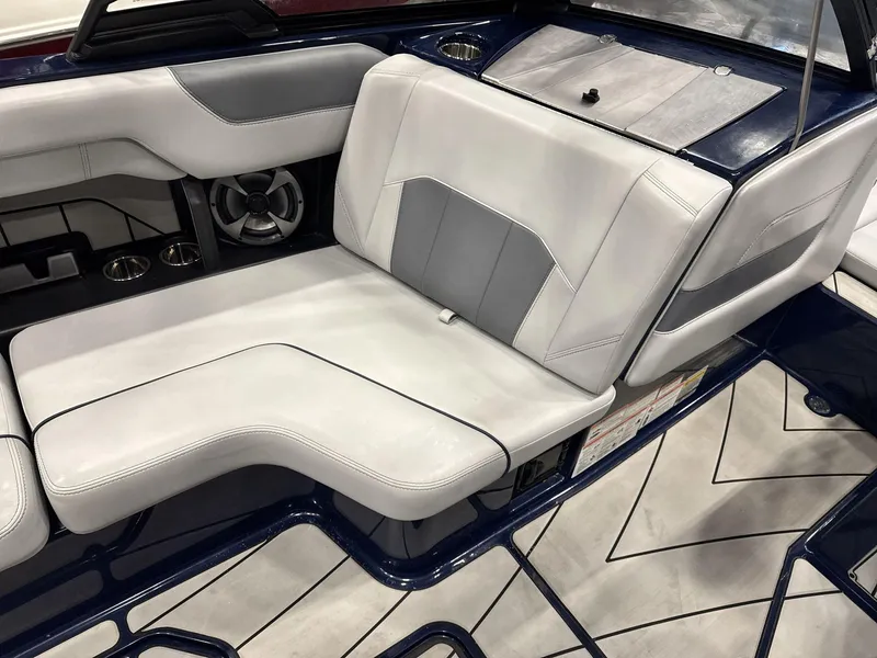 Slide: The Image of 2021 Malibu 25 LSV boat interior with white and gray seating, speaker, and cup holders. - 11
