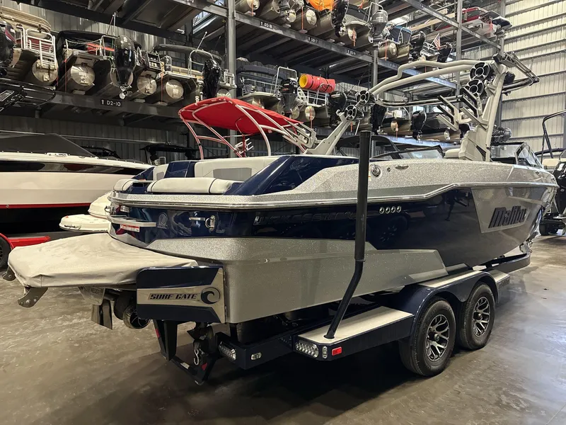 Slide: The Image of 2021 Malibu 25 LSV boat in storage, featuring sleek design and dual-axle trailer. - 5