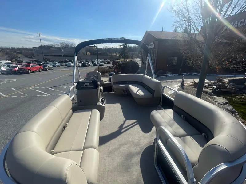 Slide: The Image of 2025 Sun Tracker Party Barge 16 DLX pontoon boat with spacious seating in a parking lot. - 2