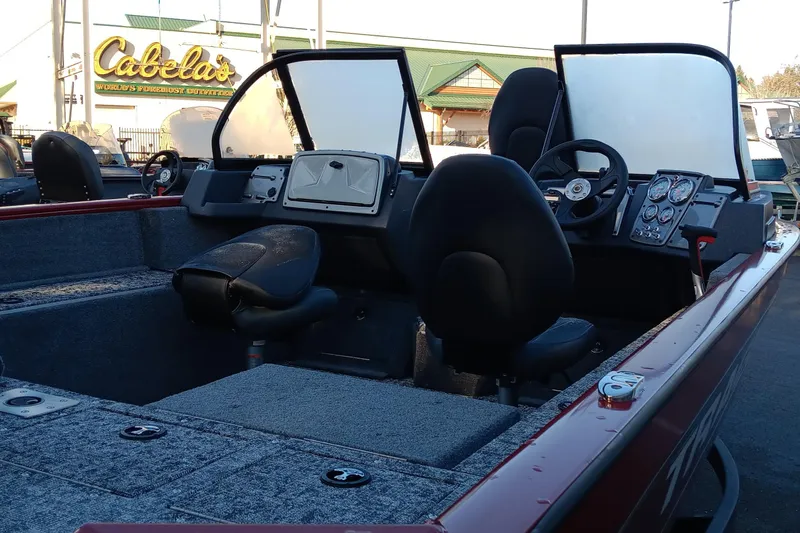 Slide: The Image of 2025 Tracker Pro Guide V-175 Combo boat interior with seating and dashboard, parked near Cabela's. - 3