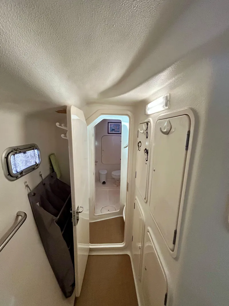 Slide: The Image of Narrow hallway inside 2001 Voyage Maxim boat, featuring storage compartments and a small window. - 23