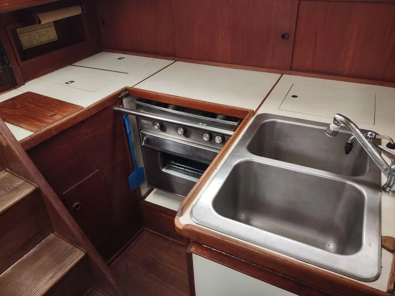Slide: The Image of 1983 Sabre 38 yacht kitchen with stove, double sink, and wooden cabinetry. - 10